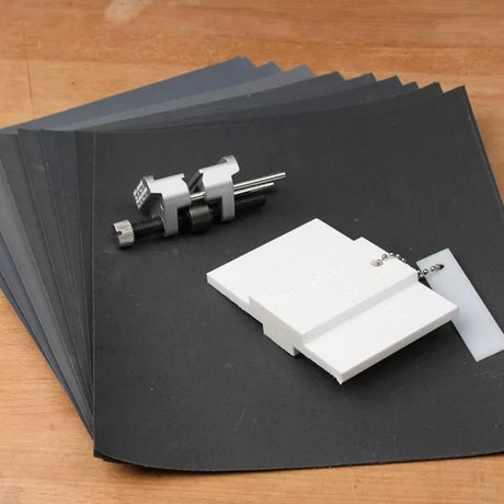 Sandpaper sheets in graded grits with a honing guide and sandpaper holder plates