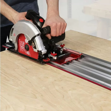 Circular saw riding on a red aluminum track saw guide rail cutting plywood