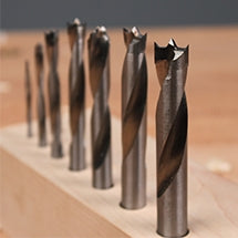 Row of brad point drill bits standing in a wooden block