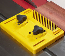 Yellow Magswitch magnetic featherboard on a table saw beside a board