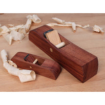 Two wooden hand planes on a bench with curled wood shavings