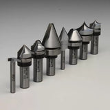 Assorted carbide-tipped router bits for woodworking, arranged in a row on a gray background.