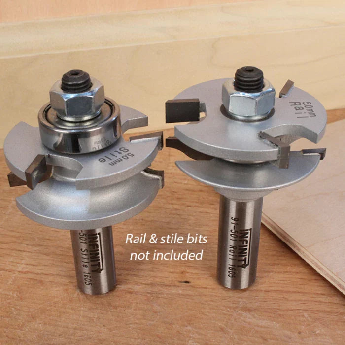 Two silver rail and stile router bits for woodworking on a wooden surface.