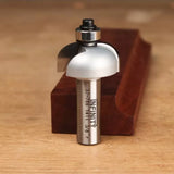 Roundover router bit with guide bearing and wood molding profile on workbench