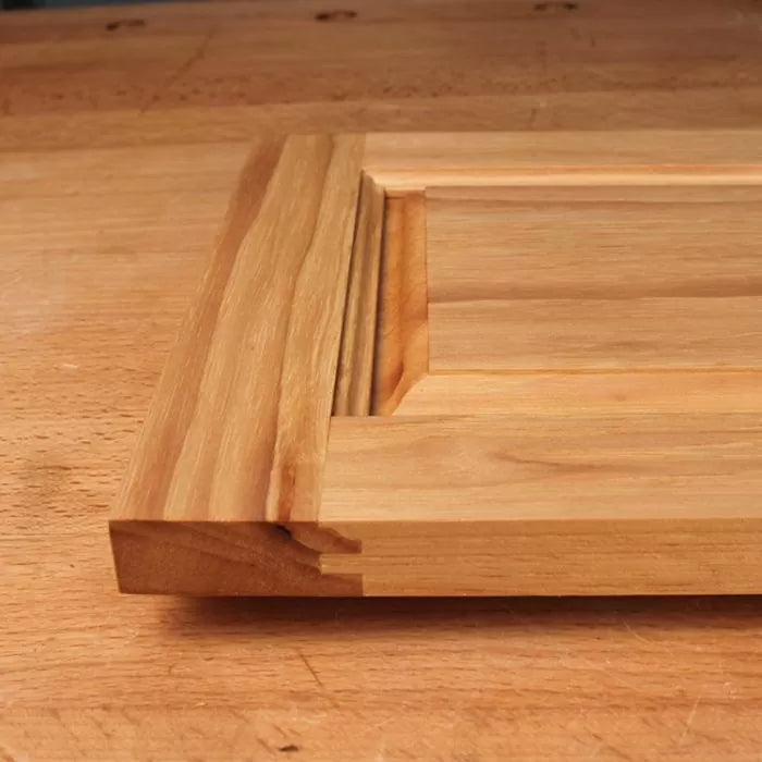 Closeup of unfinished wooden cabinet door with raised panel and decorative edge profile