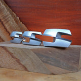 Set of three silver woodworking tenon joint jigs on stacked wood blocks, close-up view
