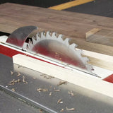 Table saw blade cutting wood, woodworking tool, dust and safety guard visible