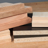 Stack of assorted hardwood and engineered wood boards on a workbench for woodworking projects
