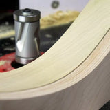Spiral flush trim router bit shaping curved wood edge on a router table, with wood shavings visible.