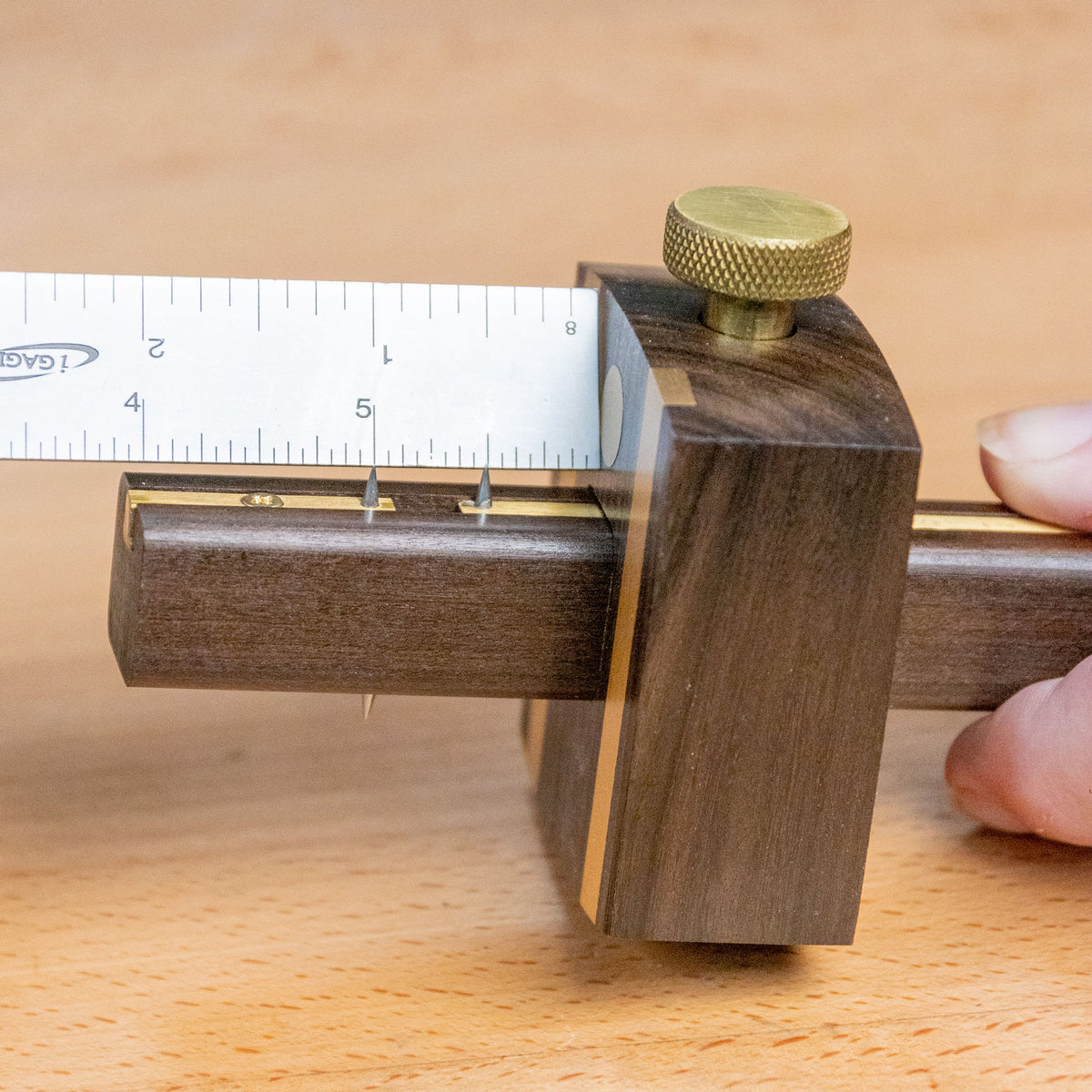 Ebony marking gauge with brass knob and ruler, woodworking layout tool on wood surface