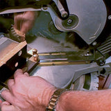 Hand adjusting woodworking jig on miter saw for precise wood cutting