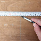 Hand marking measurements on wood with a steel ruler for woodworking precision