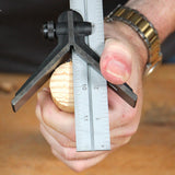 Woodworking center finder tool measuring round wooden dowel on workbench
