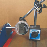 Digital indicator gauge with magnetic base measuring saw blade alignment on a woodworking table.