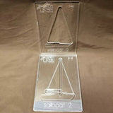 Clear acrylic sailboat template set for woodworking projects on a brown surface