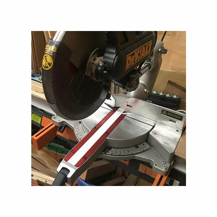 Sliding compound miter saw with red and white miter gauge in woodworking shop
