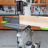 Bandsaw cutting a thick wood board with fence and push blocks in a woodworking shop
