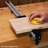 Woodworker sanding board on workbench with aluminum T-track clamp and back-to-back adaptors