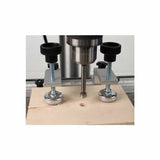 Drill press with woodworking hold-down clamps securing wood for precise drilling