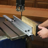 Band saw with aluminum fence cutting wood in woodworking shop setting