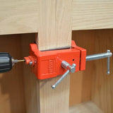 Red woodworking corner clamp holding wood pieces with power drill for precise joinery