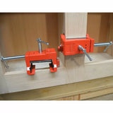 Red woodworking corner clamps securing wood panels for cabinet frame assembly
