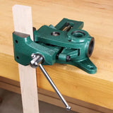 Green woodworking drill press vise mounted on workbench, holding a wooden piece vertically