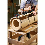 Woodworker using clamps to bend and glue cylindrical MDF form in woodworking shop