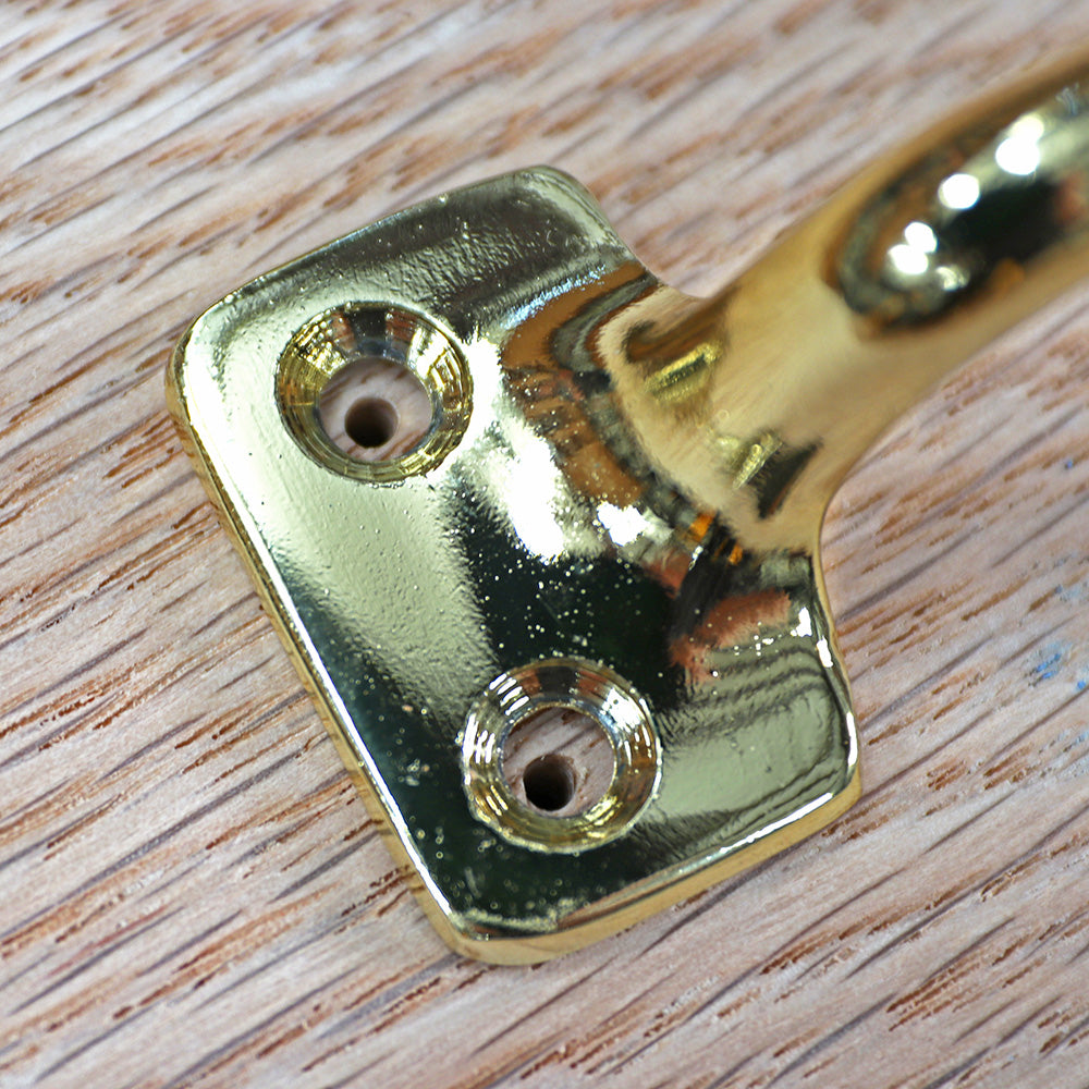 Brass hardware mounting plate with screw holes on finished wood surface