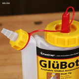 Glue bottle with yellow cap and red tethered nozzle on a wood surface, woodworking tool
