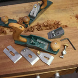 Woodworking hand plane with disassembled parts on a workbench, wood shavings visible