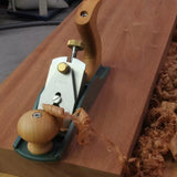 Hand plane smoothing a wooden board with wood shavings, woodworking tool in use