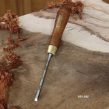 Woodworking chisel with wooden handle resting on unfinished wood with wood shavings