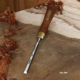 Woodworking chisel with wooden handle on burl wood, surrounded by wood shavings
