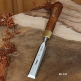 Wood chisel with wooden handle and sharp steel blade on a workbench with wood shavings