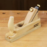 Wood hand plane tool with brass adjustment knob on a woodworking bench