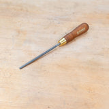 A round rasp sitting on a wooden bench.