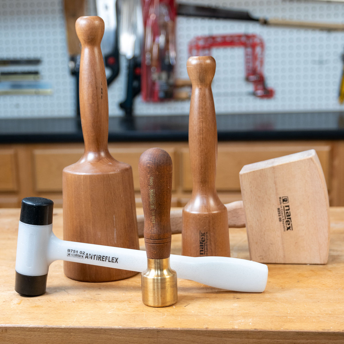 Woodworking mallet set with wood and brass handles on a workbench in a workshop.