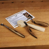 Wood carving tools set with spoon blank and instructions on a wooden workbench