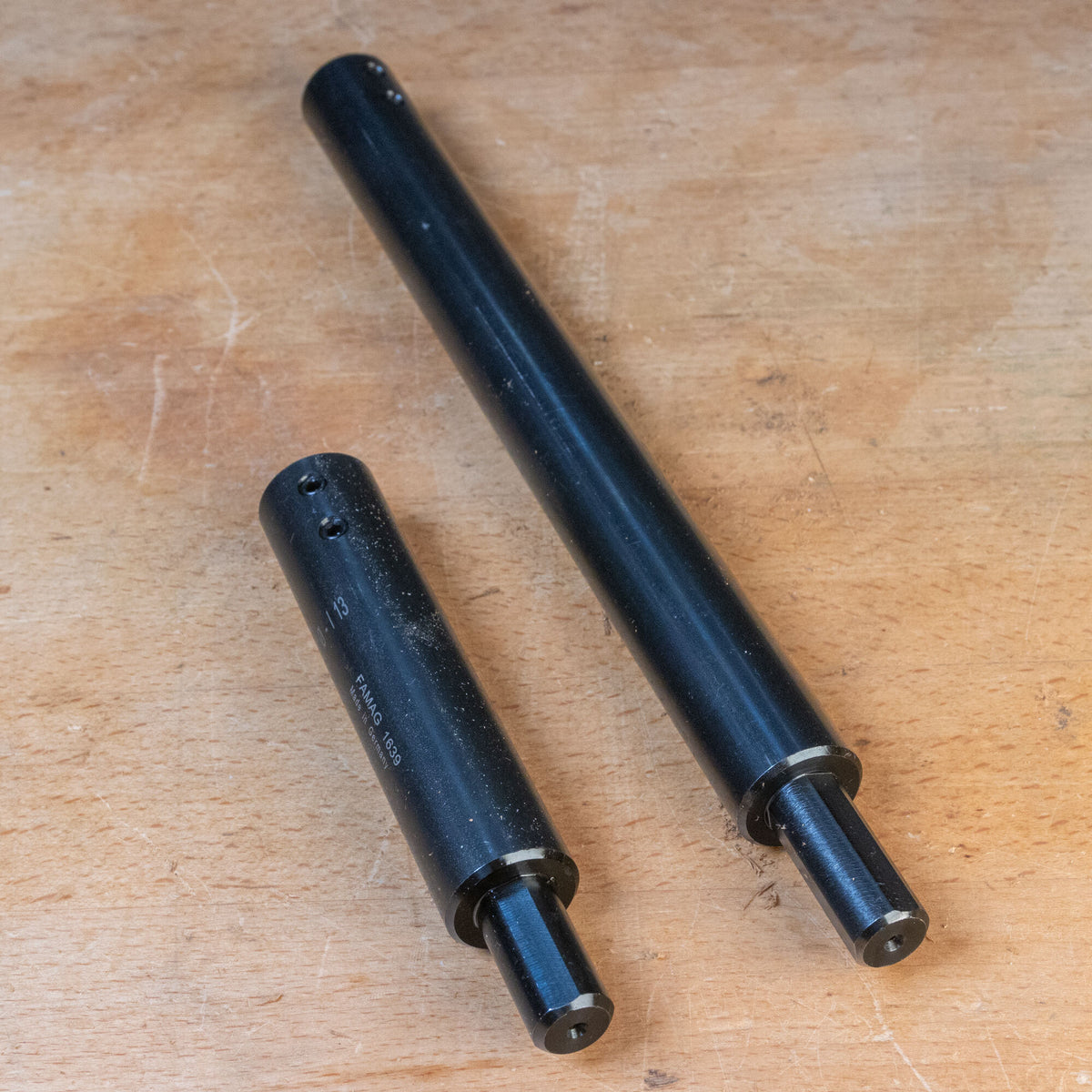 Two black steel router table extension rods on a wooden surface, woodworking tool accessory