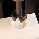 Forstner drill bit cutting a clean hole in light-colored wood panel