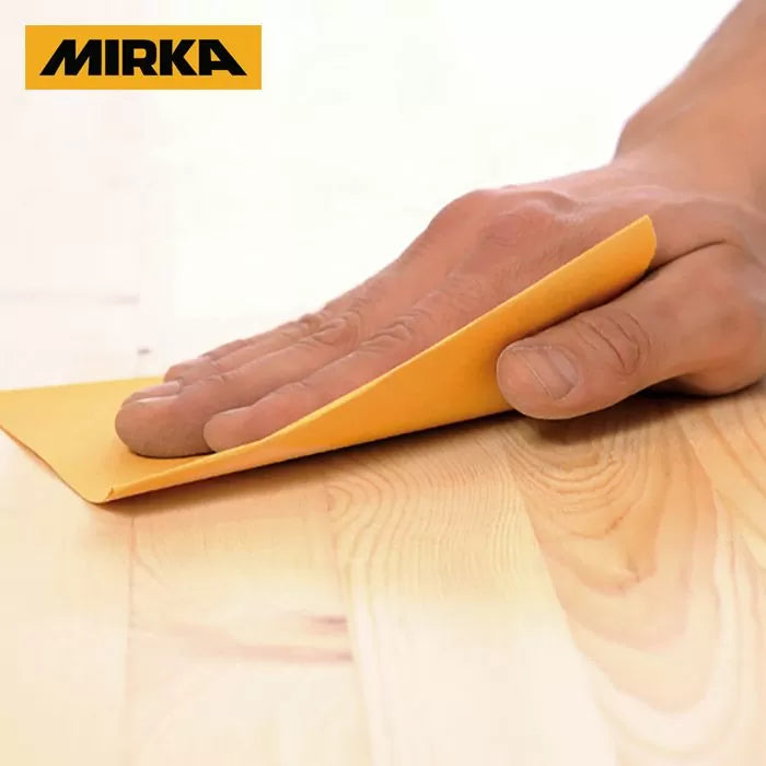 Hand sanding wood surface with yellow sandpaper, Mirka logo visible in corner