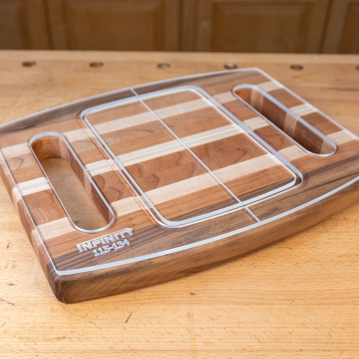 Acrylic cutting board template overlay on a striped wood cutting board with handle slots.