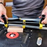 Woodworker using router table jig with yellow and black handles to guide wood block