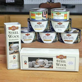 Liberon steel wool and various Black Bison wax polish tins for woodworking on a workbench