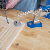 Woodworking bench clamp securing a wooden board while a drill drives a screw