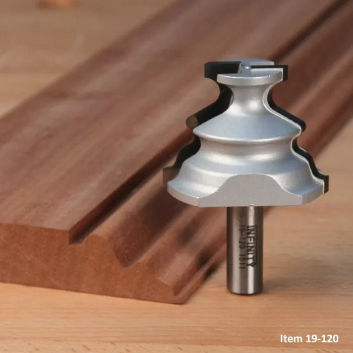 Woodworking router bit with intricate profile beside a decorative wood moulding on a workbench