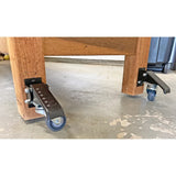 Heavy-duty workbench casters with foot levers attached to wooden legs on workshop floor