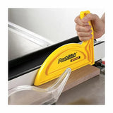 Yellow push stick guiding wood on a table saw for woodworking safety