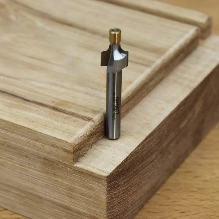 Straight router bit with bearing on a wooden dado joint, used for precise woodworking cuts.